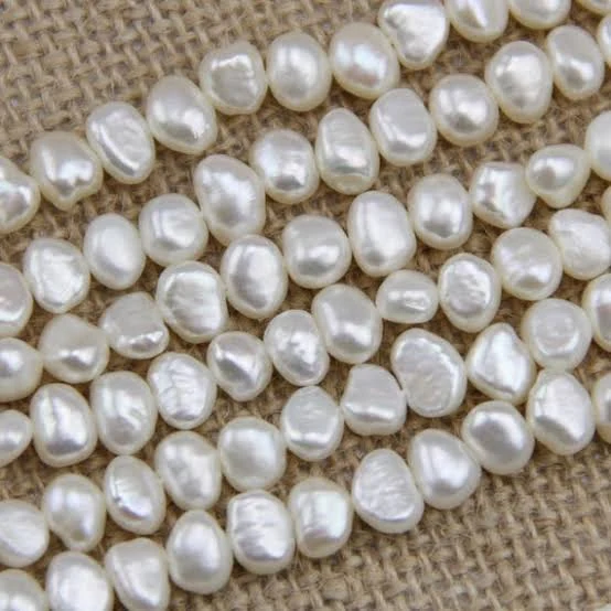 White baroque freshwater pearl strands arranged on natural burlap